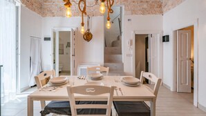 A dining area with a brick ceiling, hanging light fixtures, and a staircase in the background. - Dimora Oliver by Rentbeat  (Ostuni)