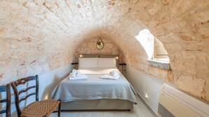 A cozy attic bedroom with a bed, a chair, and a small table. - Dimora Oliver by Rentbeat  (Ostuni)