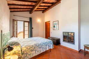 A bedroom with a bed, a nightstand, a lamp, a window with a view, and a door.