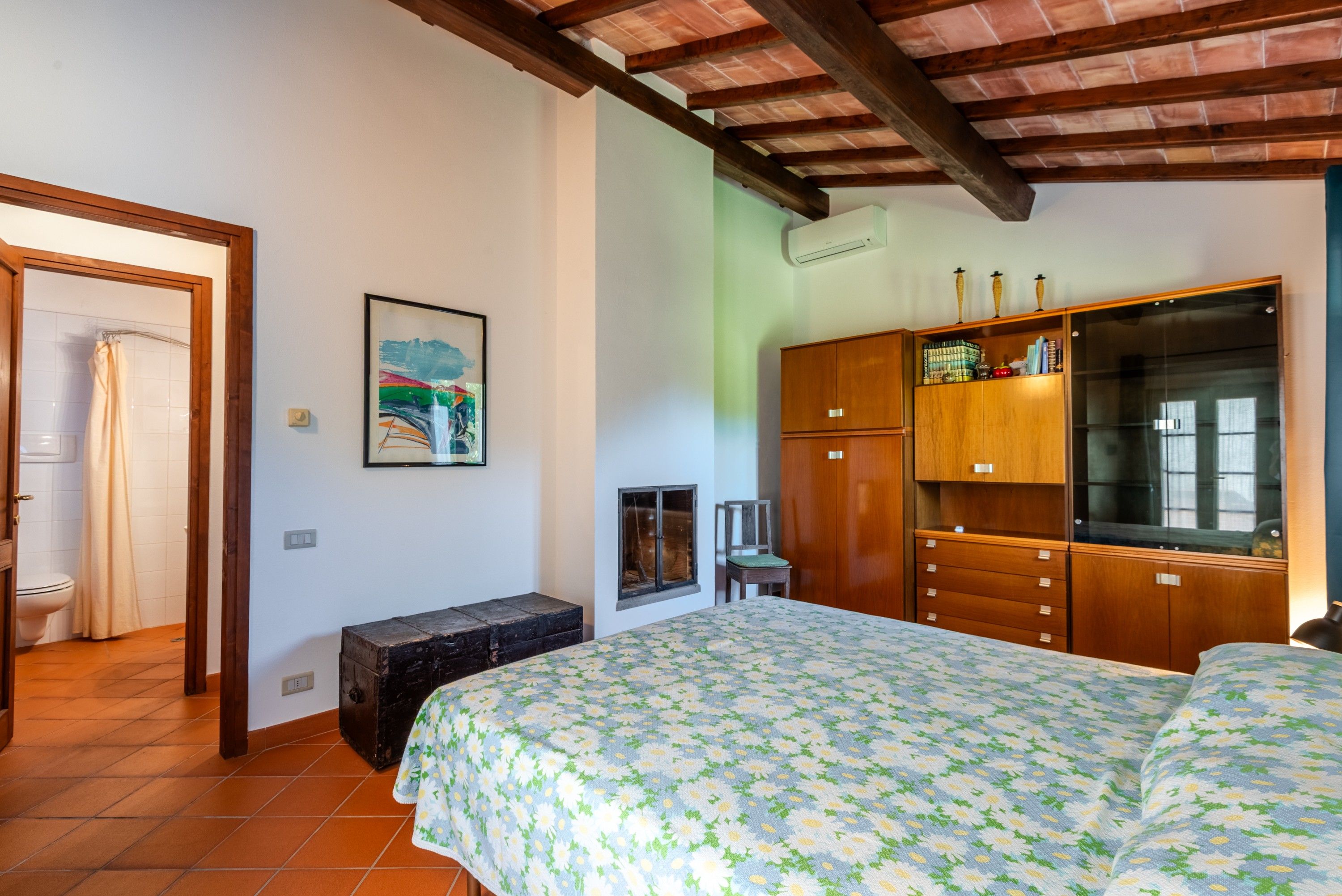 Une chambre à coucher avec un lit, une armoire en bois, un banc et un tableau accroché au mur.