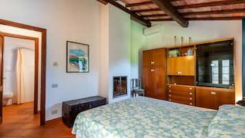 Une chambre à coucher avec un lit, une armoire en bois, un banc et un tableau accroché au mur.