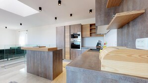 A modern kitchen with built-in appliances, a glass railing, and a mezzanine level.