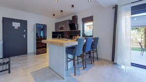 A modern kitchen with a central island, bar stools, and a view of the outdoors. - Stunning apartment in Drenje with WiFi (Drenje)