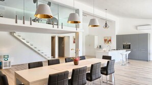 A modern kitchen with grey cabinets, a central island, and a dining area with a long table and black chairs. - Beautiful home in Rovinjsko selo (Rovinjsko selo)