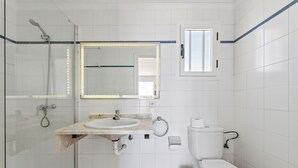 A bathroom with a shower, sink, toilet, and a mirror with lights. - Apartamento Mar Azul (Puerto del Carmen)