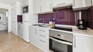 A modern kitchen with white cabinets, a stainless steel oven, a microwave, and a coffee maker. - Apartamento Mar Azul (Puerto del Carmen)