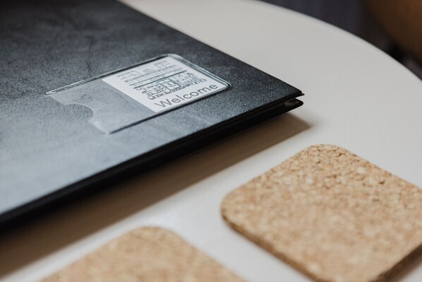A black folder with a welcome sticker on a white surface with cork tiles.