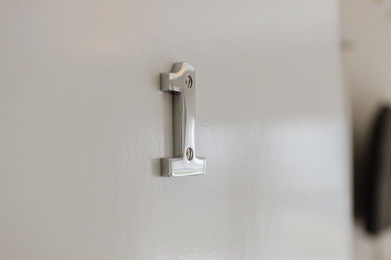 Eine metallene Türgriff an einer weißen Tür.
