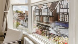 A room with a view of traditional half-timbered houses, a radiator, and a chair by the window. - Grace`s Guesthouse Room 5 (Tring)