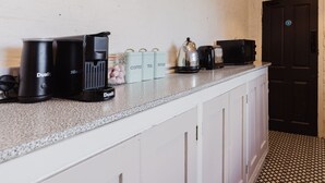 Een aanrecht met een koffiezetapparaat, een broodrooster en potten met koffie, thee en suiker.