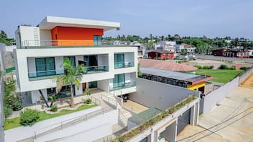 Un immeuble moderne à plusieurs étages, doté de balcons, d’un abri pour voitures et d’un jardin aménagé.