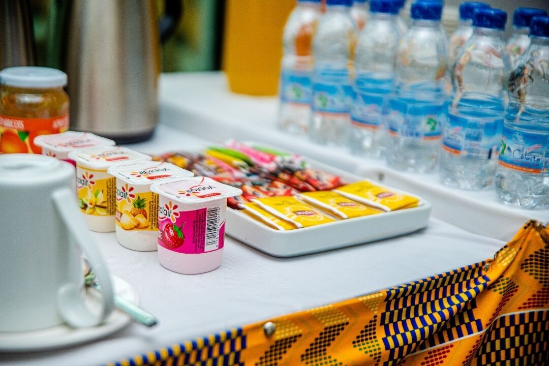 A buffet table with various food items, including yogurt cups, packaged snacks, and bottled water.