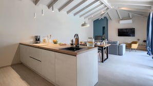 A modern kitchen with a central island, a dining area with a table and chairs, and a living room with a sofa and a TV. - Lovely home in Rovinjsko selo with sauna (Rovinjsko selo)