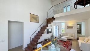 A spacious living area with a staircase, a sofa, a coffee table, and a dining table.