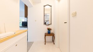 A hallway with a wooden bench, a small table with a vase, and a mirror on the wall.