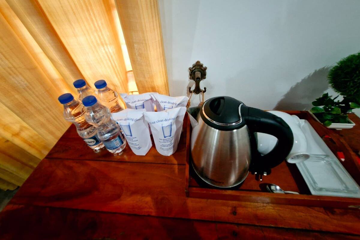 A wooden table with water bottles, a kettle, and a small statue.