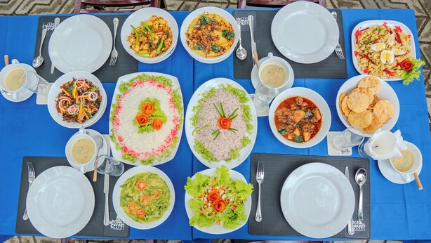 Una mesa dispuesta con diversos platos, como arroz, ensaladas y sopas, sobre un mantel azul.