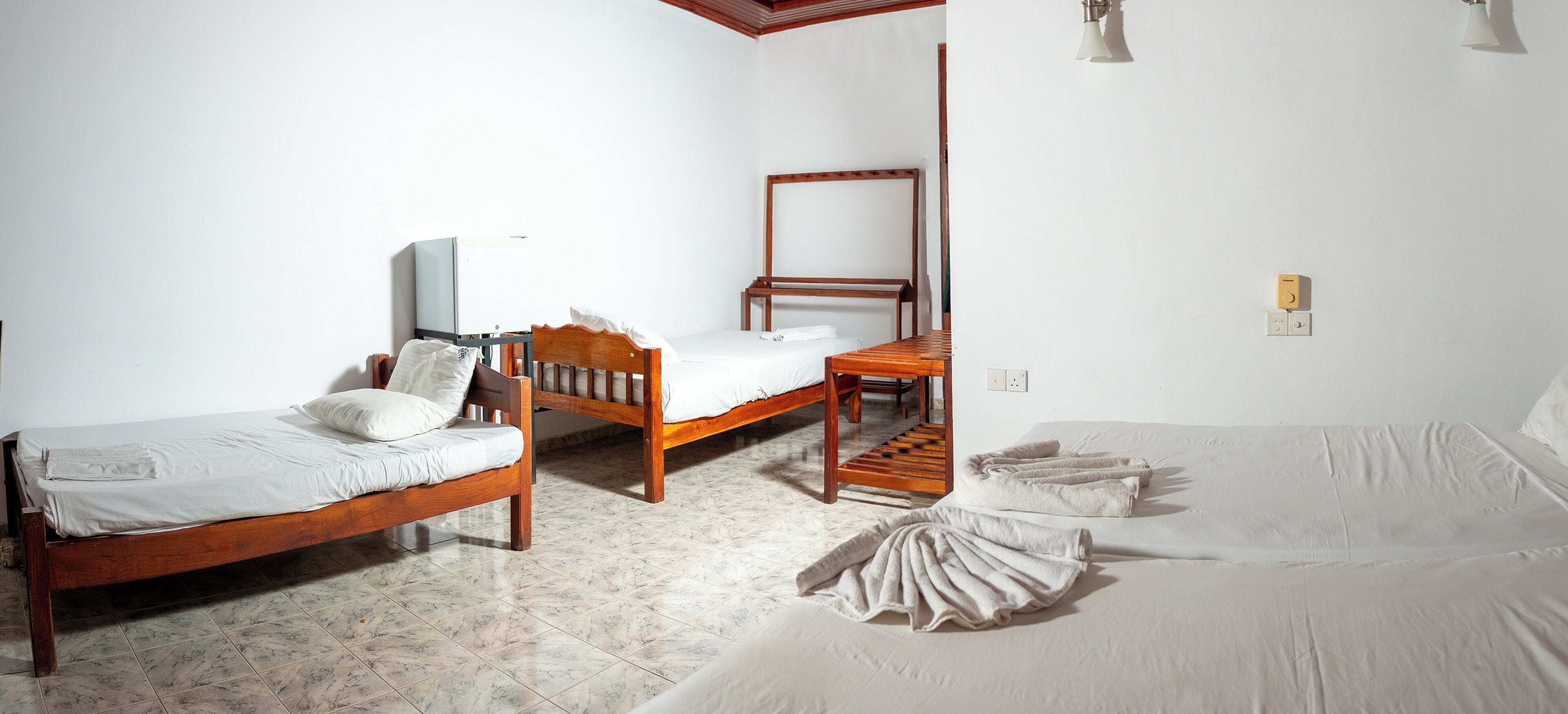 A hotel room with two single beds, a wooden desk, a television, and a small table.