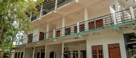 Un immeuble à plusieurs étages doté d’un balcon à l’étage supérieur, d’une zone couverte avec un toit et d’un escalier menant à l’étage supérieur.