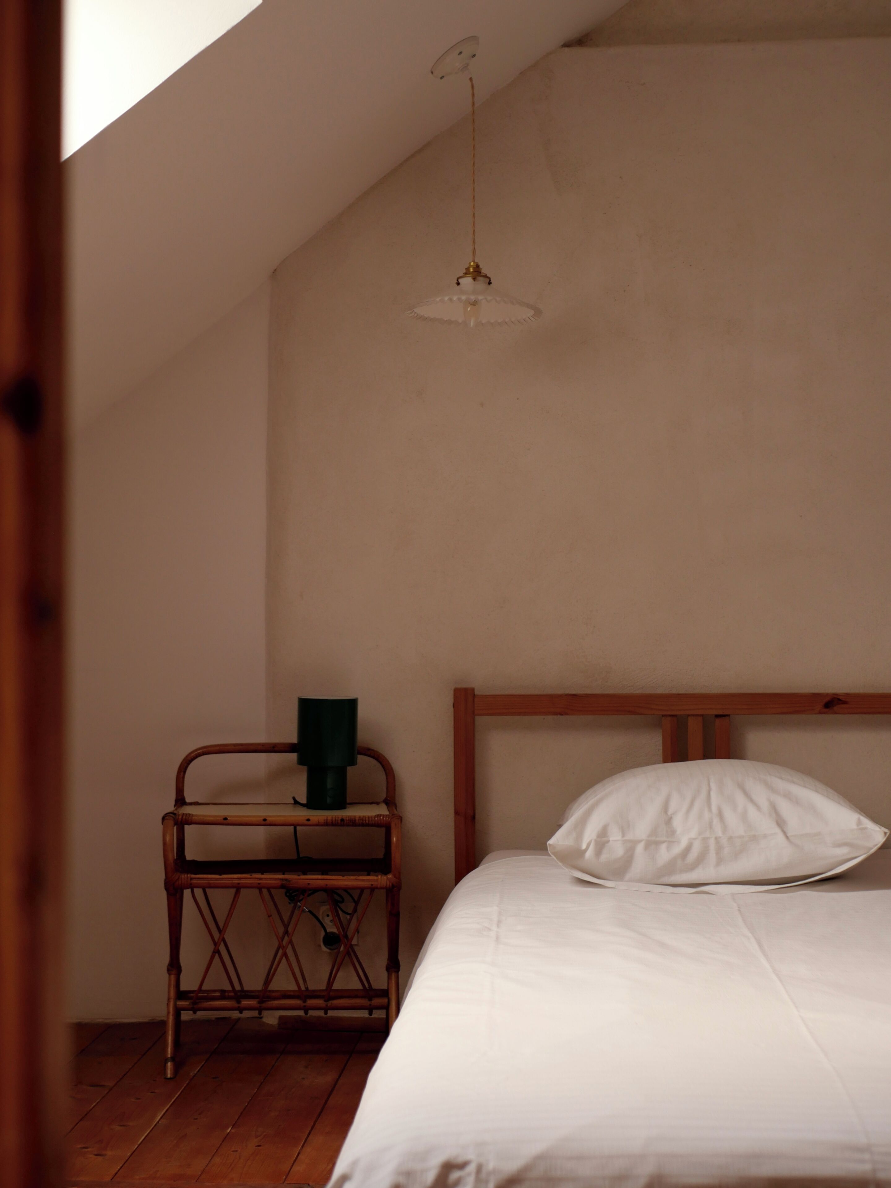 Une chambre à coucher avec un lit en bois, une table de chevet et un luminaire suspendu.