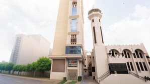 Un edificio alto con una torre destacada y un letrero para el Hotel Sama Zahr.