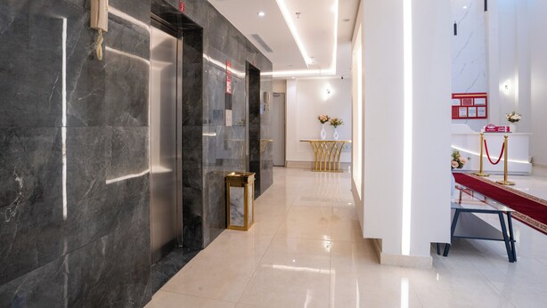Un moderno vestíbulo de hotel con paredes de mármol, un mostrador de recepción y una zona alfombrada de color rojo.