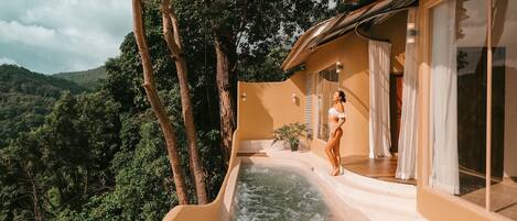 A modern villa with a private hot tub, large windows, and a scenic mountain view.