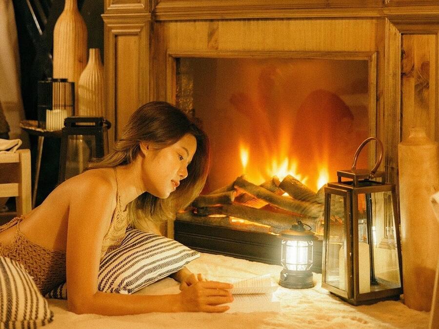 A cozy room with a fireplace, a bed, a nightstand, and a window with curtains.