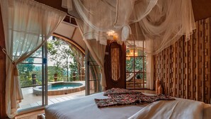 A bedroom with a large bed, a view of a hot tub, and a bamboo wall. - Lannawild Chiang Mai (Mae On)