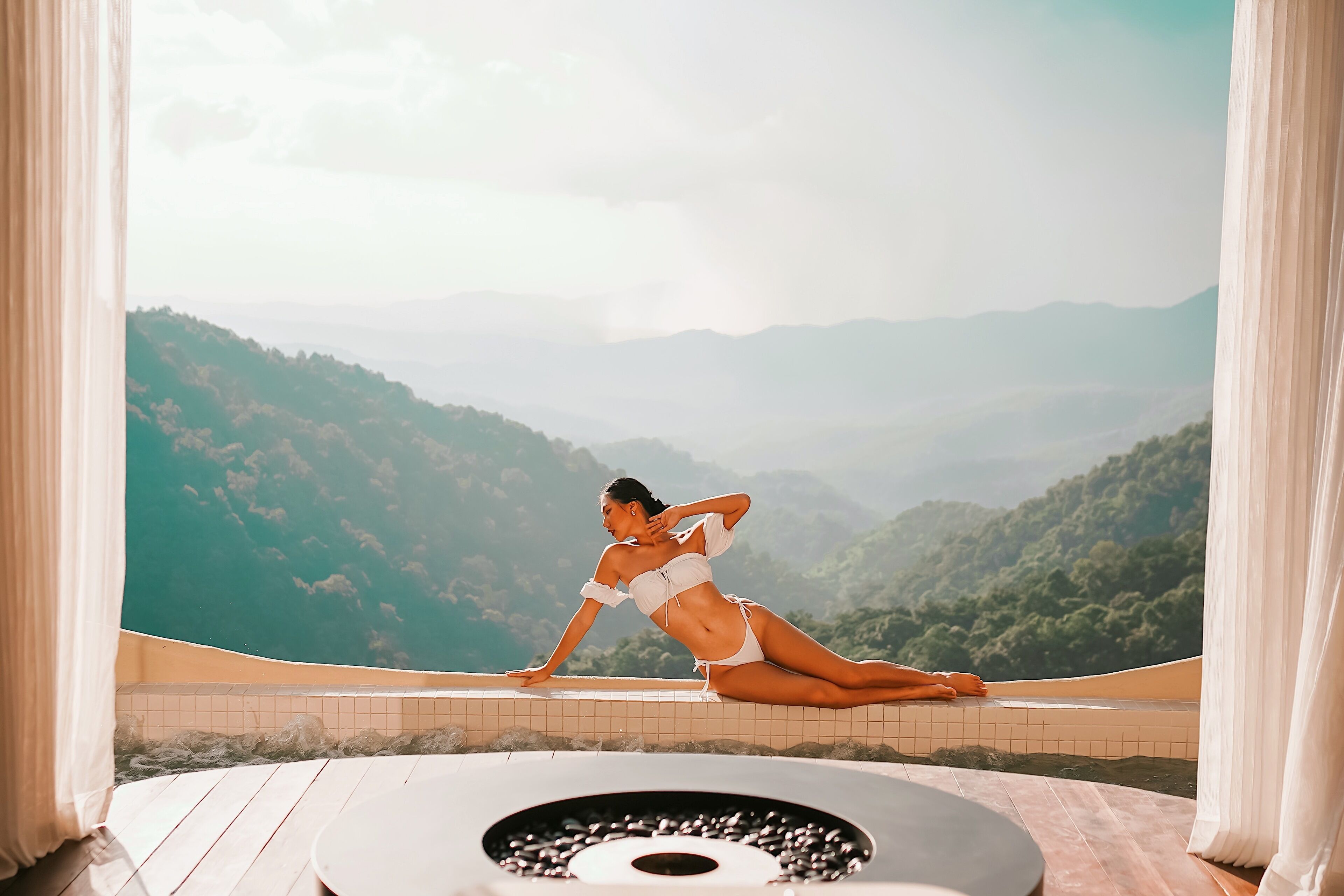 Una persona en traje de baño en un balcón con vistas a montañas.
