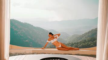 Una persona en traje de baño en un balcón con vistas a montañas.