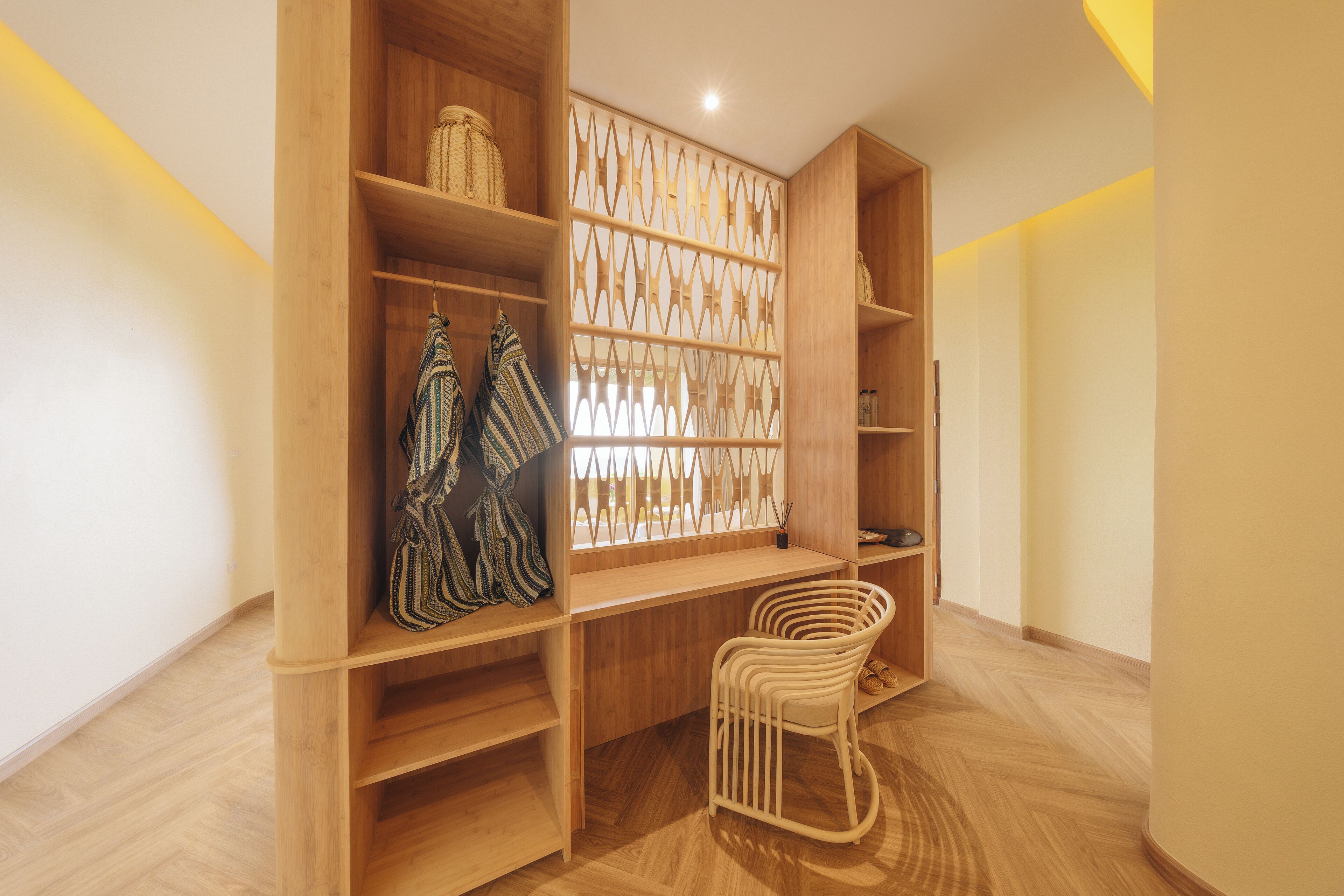 Une pièce avec des étagères en bois, un élément de séparation décoratif et un fauteuil en osier.