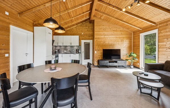 A modern log cabin interior with a dining area, kitchen, living room, and a large window offering a view of the outdoors. - Gorgeous home in Haren with WiFi (Haren)