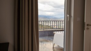 A room with a view of a distant landscape through a window with a metal railing.