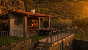 A stone building with a fireplace, outdoor seating, and a staircase leading to a balcony. - Luxury Douro Villa with Pool & Panoramic Views (Ferreiros de Avões)