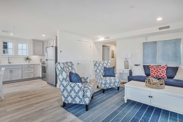 A modern living room with two patterned armchairs, a blue sofa, and a white cabinet.