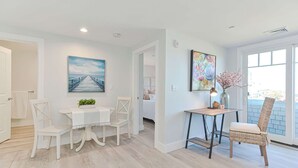 Un interior moderno con comedor, una pequeña mesa con lámpara y una silla de mimbre.
