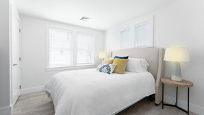 Een slaapkamer met een bed, twee bedlampjes en een raam met jaloezieën.