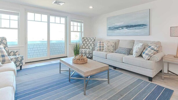 A modern living room with a white sofa, a coffee table, and a large window with a view of the sea. - Premium Ocean View Condo (1,100S.F.) (Plymouth)