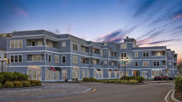 A multi-story hotel with a modern architectural design, featuring a prominent entrance with a sign, landscaped gardens, and a well-maintained driveway.