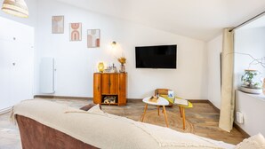 Ein modernes Wohnzimmer mit Flachbildfernseher, einer Holzkassette, einer Couch und einem kleinen Tisch.