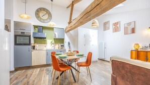 Eine moderne Küche mit Essbereich, Holzbalken und einer Uhr an der Wand.