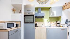Eine kleine Küche mit Mikrowelle, Backofen und modernen Geräten.