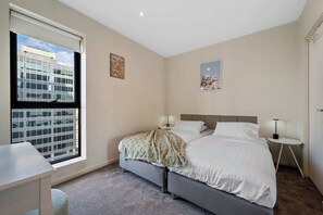 Een hotelkamer met een bed, nachtkastjes, een raam met uitzicht op de stad en een klein bureau.