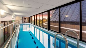 A swimming pool with a view of a cityscape through large windows.