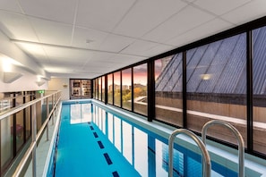 Una piscina con vistas a un paisaje urbano a través de amplios ventanales.