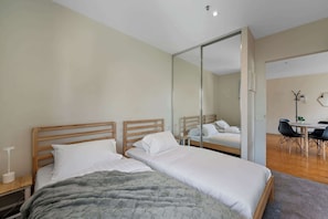 Un dormitorio moderno con dos camas de madera, un espejo grande y un escritorio con sillas.