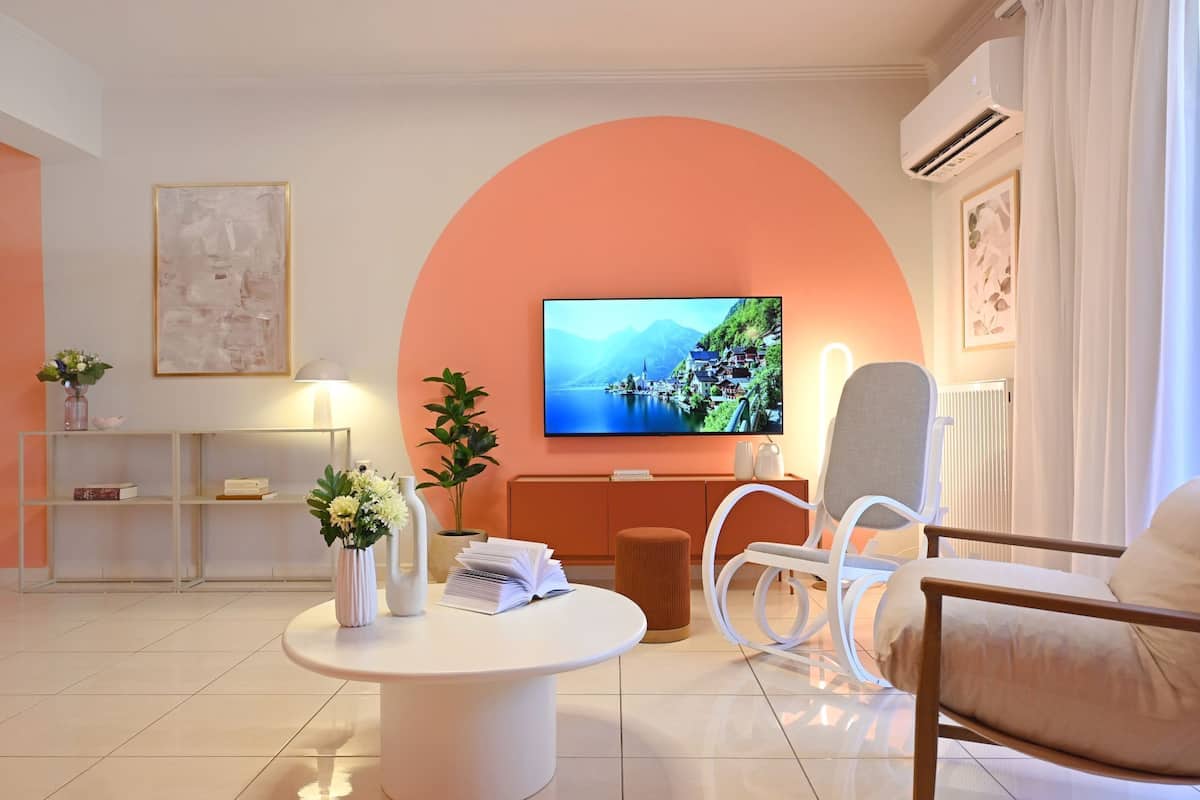 A modern living room with a large TV, a round coffee table, and two chairs.