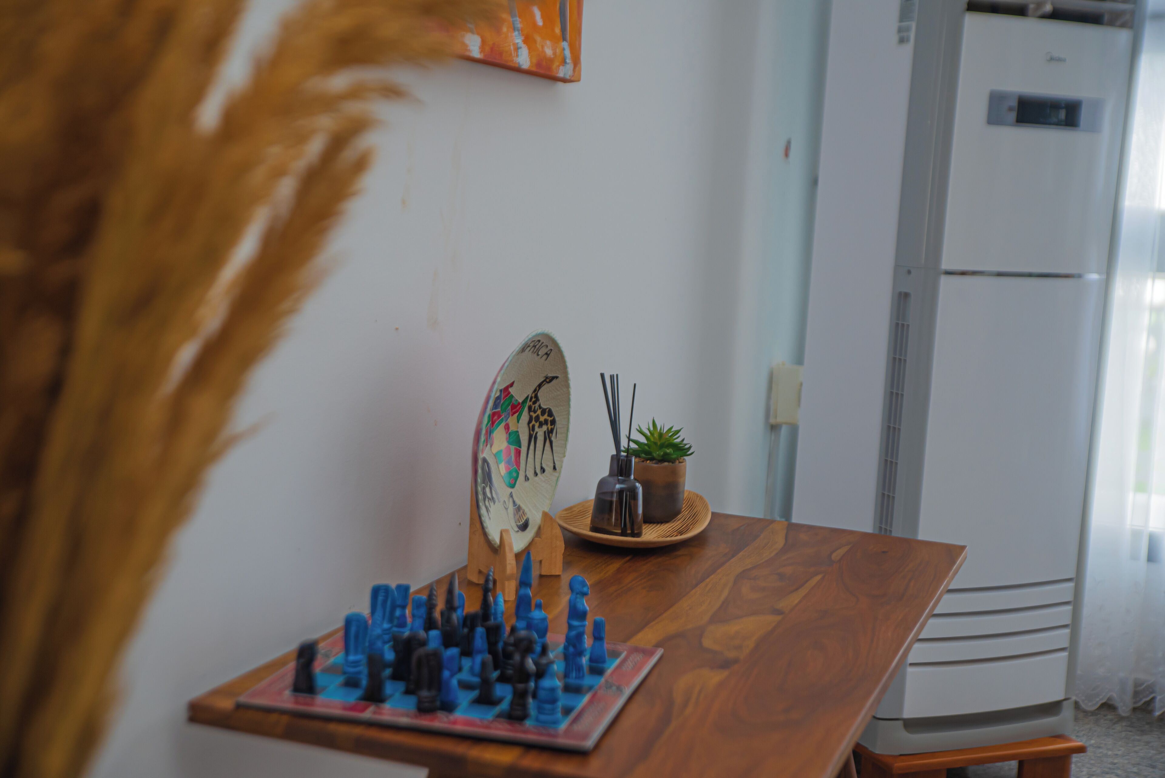 A wooden table with a chessboard, a decorative plate, and a small potted plant.