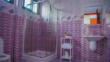 Une salle de bain avec douche, toilettes et lavabo.